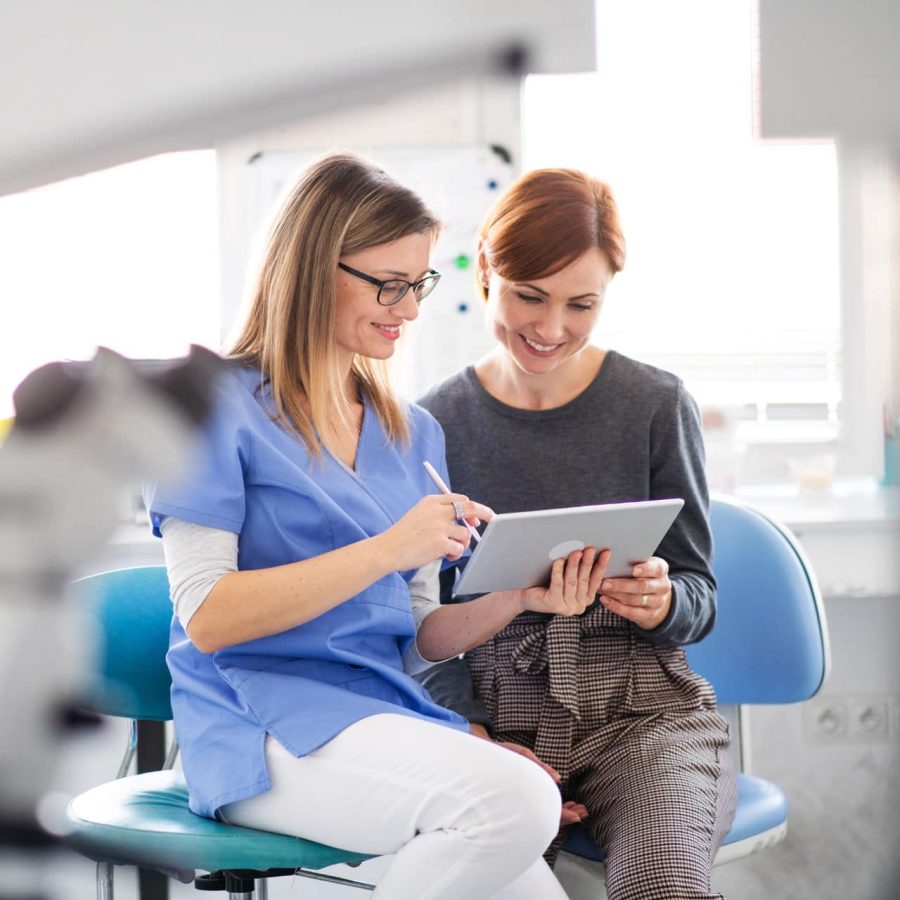 A dentist with tablet talking to woman in dentist surgery, a dental check-up.