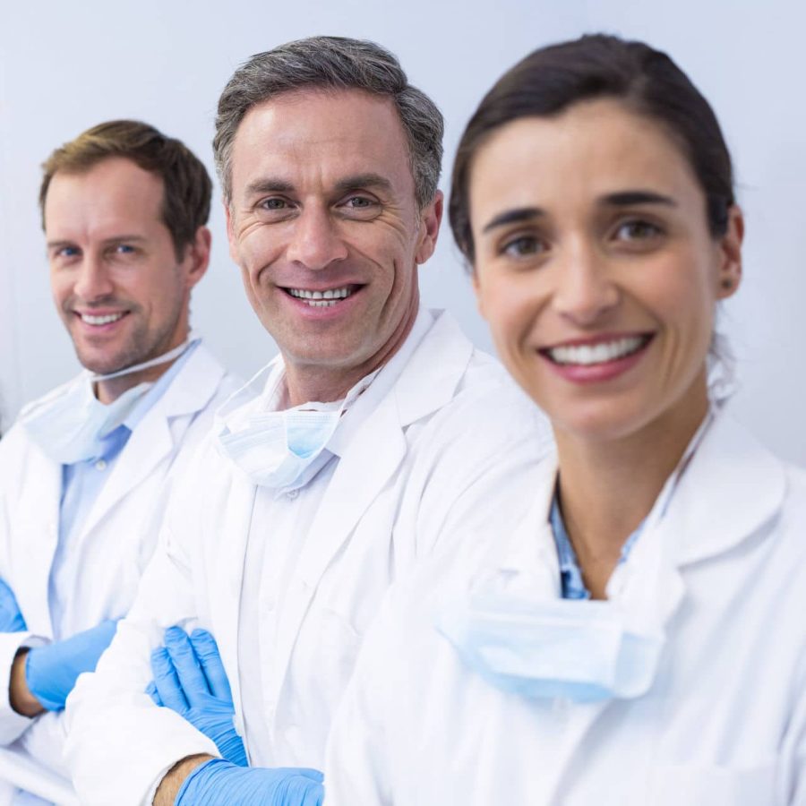 Portrait of smiling dentists standing with arms crossed in dental clinic